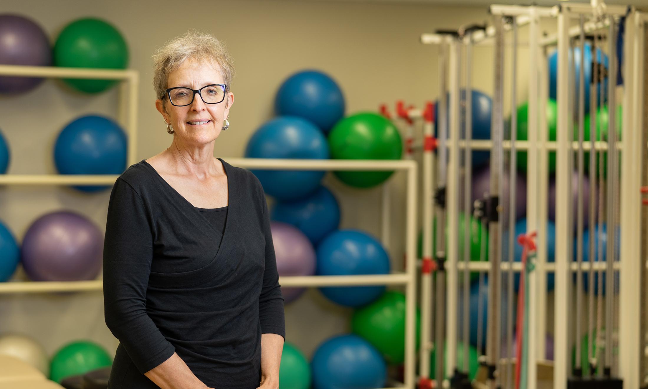 A woman standing in a room with exercise equipment behind her