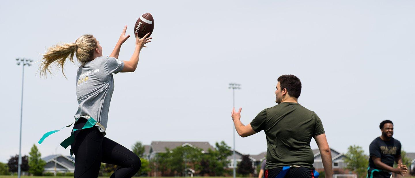 A woman catching a football in a flag football game.
